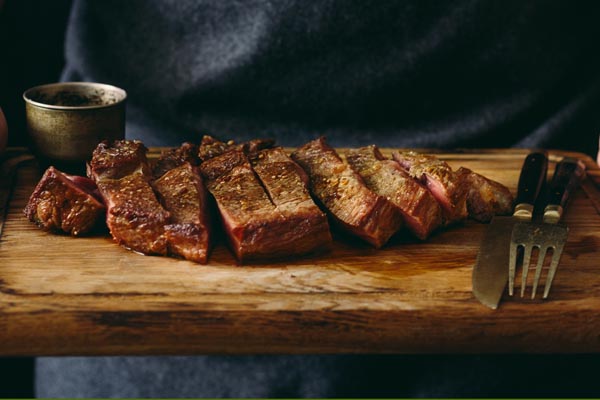 Zubereitetes Steak auf Holzbrett mit Besteck